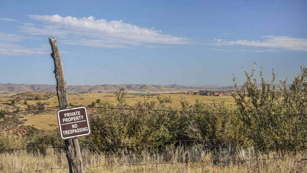 Private property, no trespassing sign on a barbed wire fence. If you were injured on someone's property while trespassing, a premises liability lawyer will not be able to help you.