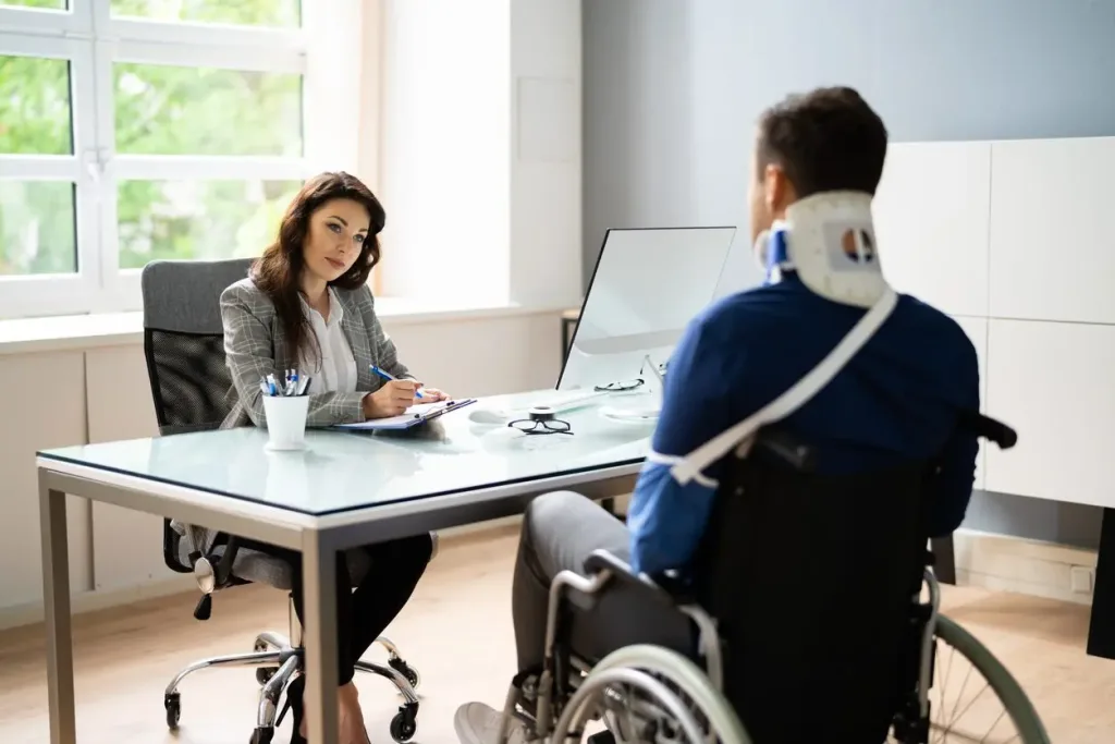 A female slip and fall lawyer speaking with an injured client in a wheelchair.
